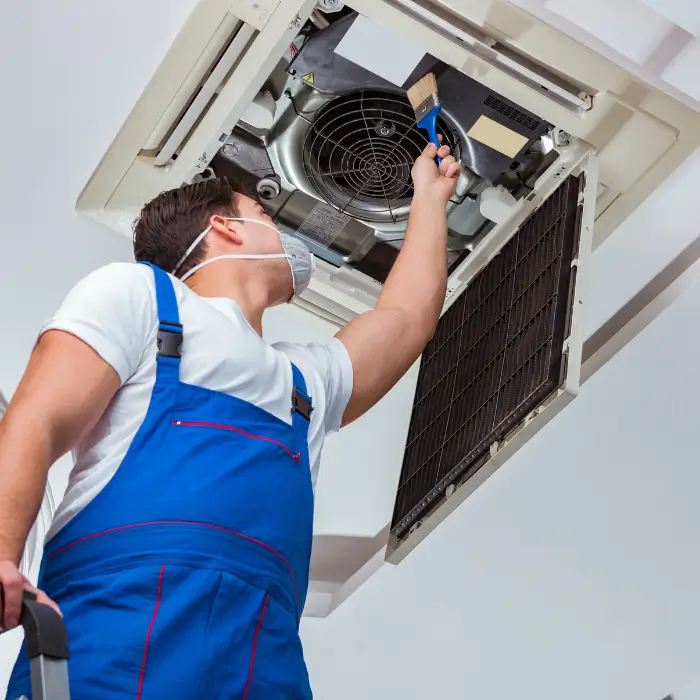 Technician cleaning ceiling air conditioner