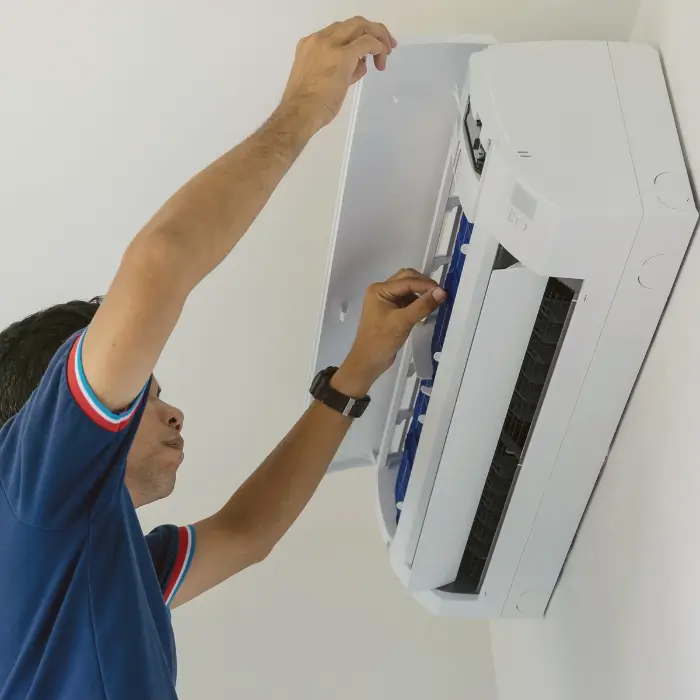 Man inspecting or repairing air conditioner unit
