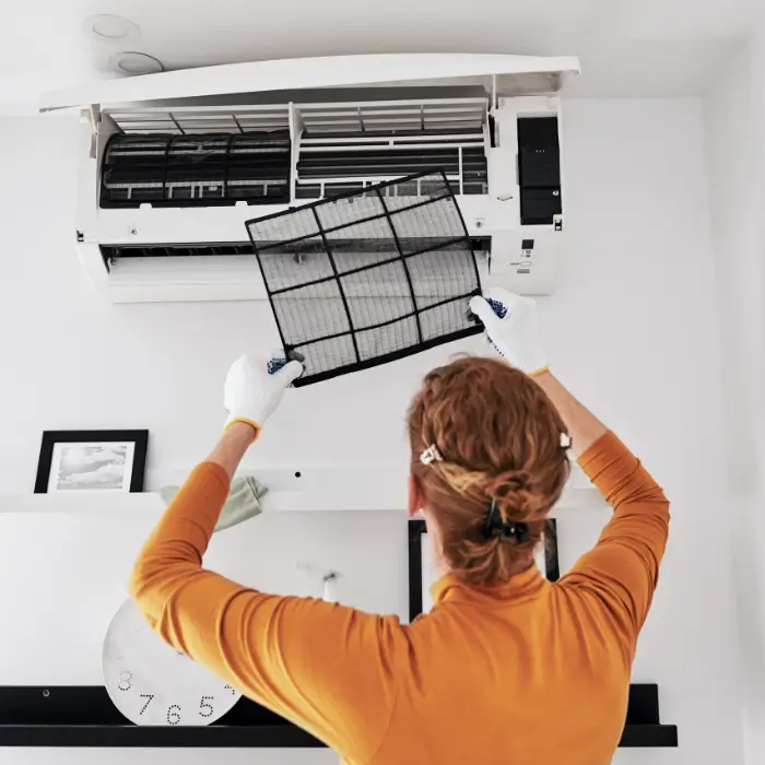 Person removing air conditioner filter for cleaning