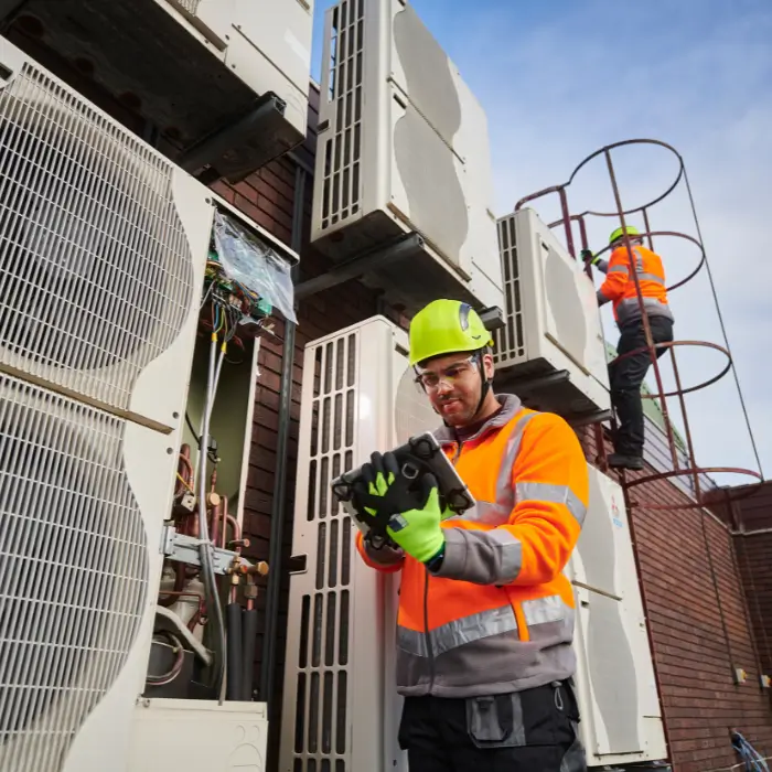 Technician testing outdoor AC unit