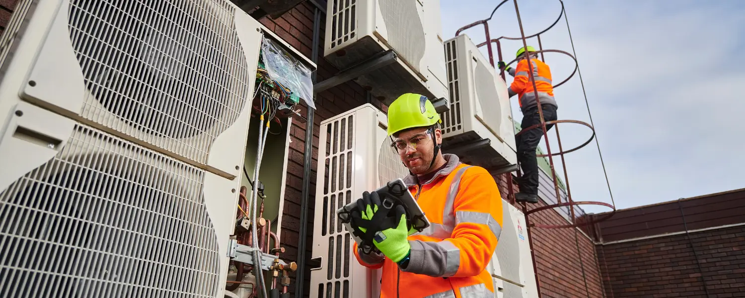 Technicians inspecting rooftop HVAC units