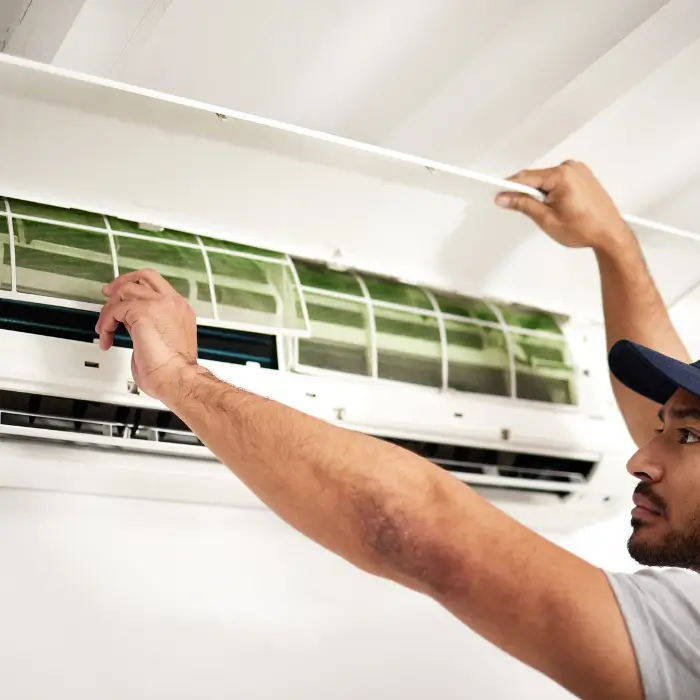 Technician removing front panel of indoor air conditioner unit